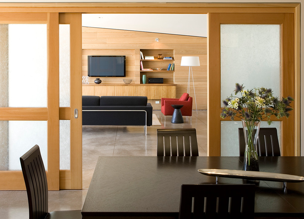 Immagine di una sala da pranzo aperta verso la cucina minimal con pavimento in cemento