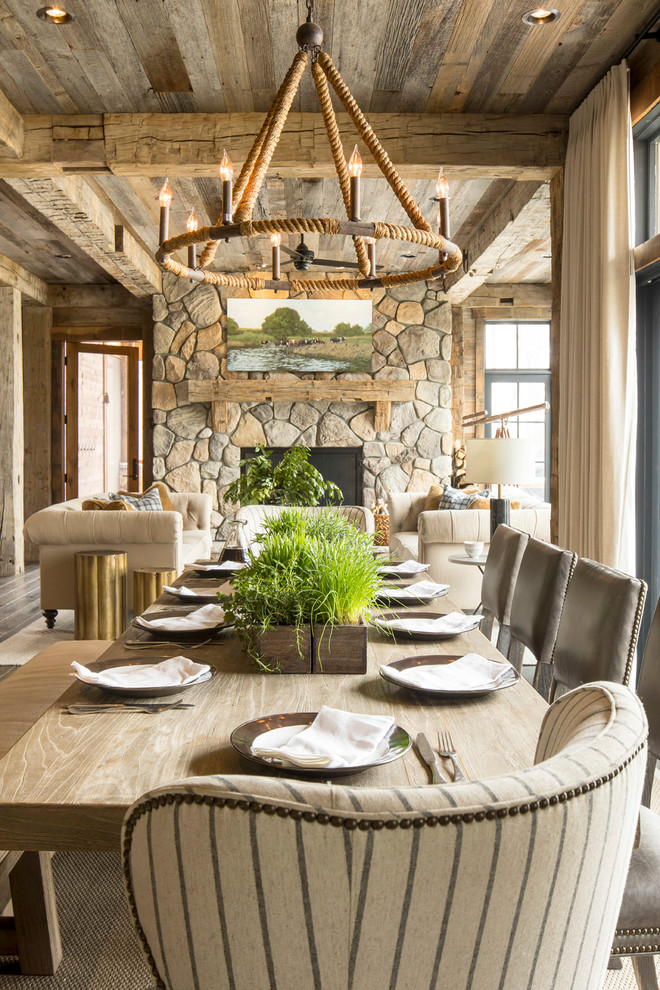 Inspiration pour une grande salle à manger ouverte sur le salon chalet avec un mur marron, parquet foncé, une cheminée standard, un manteau de cheminée en pierre, un sol marron et éclairage.