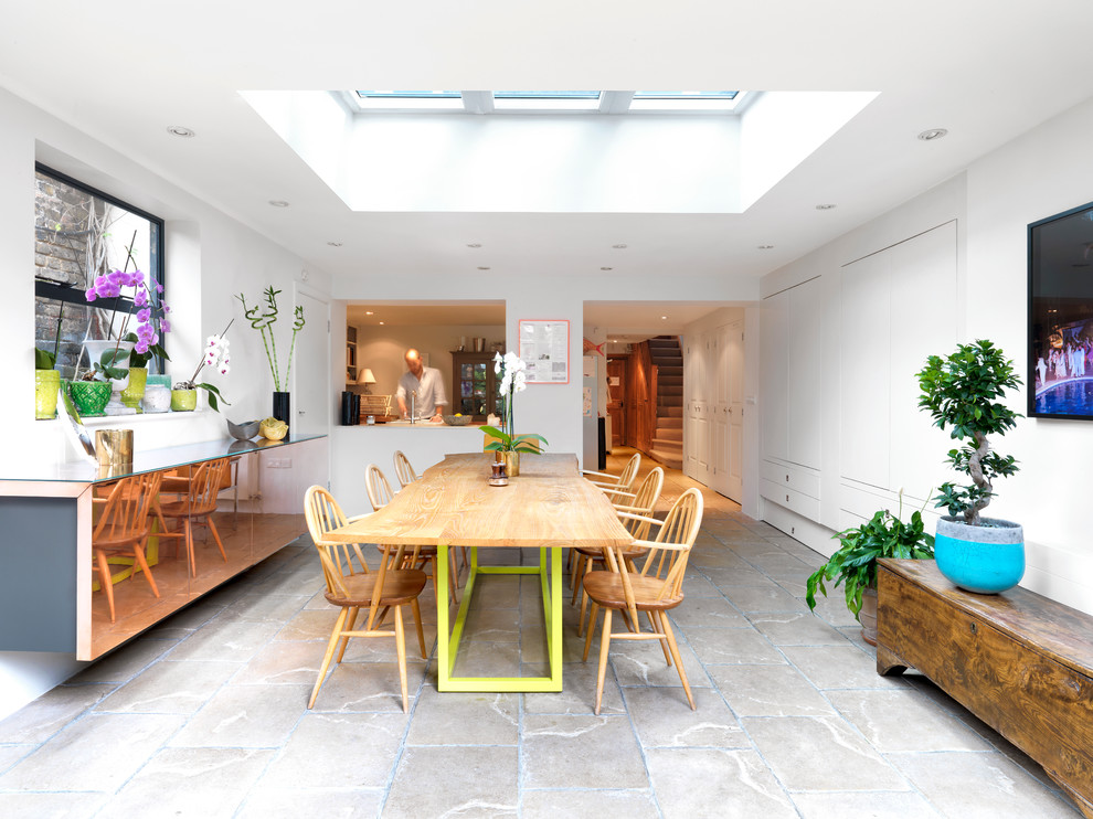 Immagine di una sala da pranzo aperta verso la cucina design di medie dimensioni con pareti bianche e pavimento in pietra calcarea