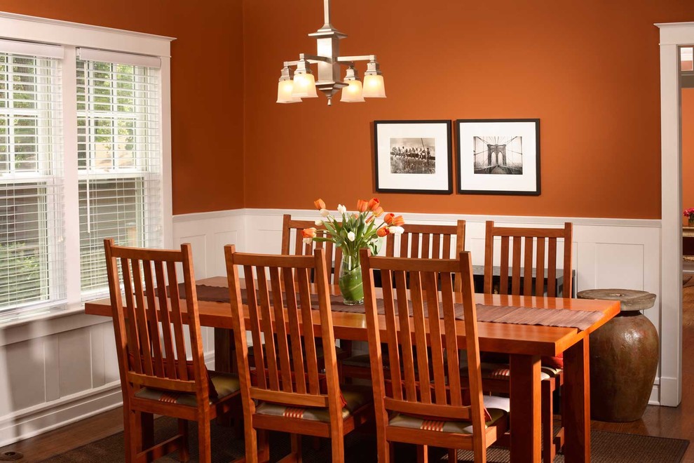 Aménagement d'une petite salle à manger ouverte sur la cuisine classique avec un mur orange et un sol en bois brun.