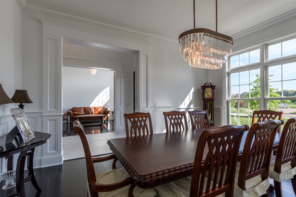 This is an example of a traditional dining room in Cleveland with white walls and dark hardwood flooring.