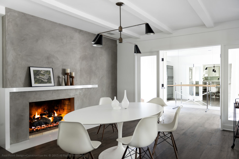 Idées déco pour une grande salle à manger ouverte sur la cuisine contemporaine avec un mur blanc, un sol en bois brun, une cheminée standard et un manteau de cheminée en béton.