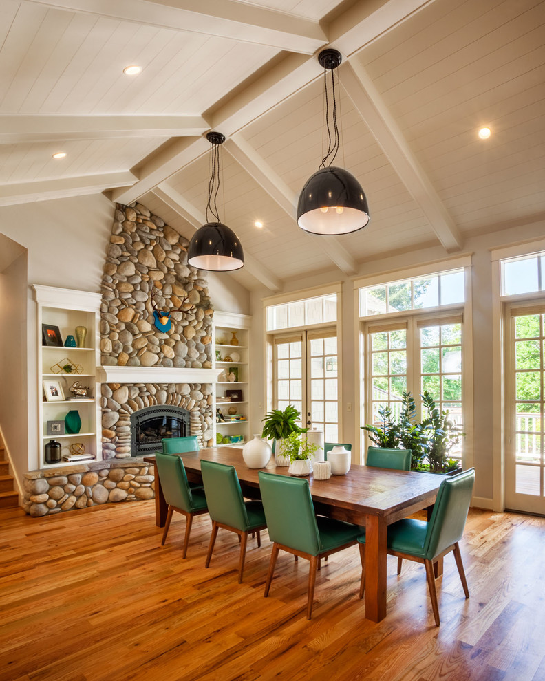 Cette image montre une salle à manger ouverte sur le salon traditionnelle de taille moyenne avec un mur blanc, un manteau de cheminée en pierre, un sol en bois brun et un poêle à bois.