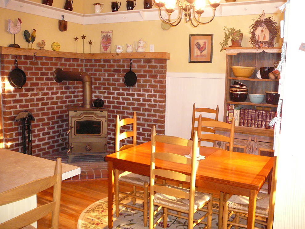 Foto de comedor de estilo de casa de campo grande abierto con paredes amarillas, suelo de madera en tonos medios, estufa de leña y marco de chimenea de ladrillo