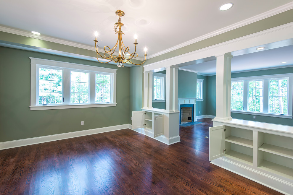 Medium sized enclosed dining room in Other with dark hardwood flooring, green walls, a standard fireplace, a wooden fireplace surround and feature lighting.