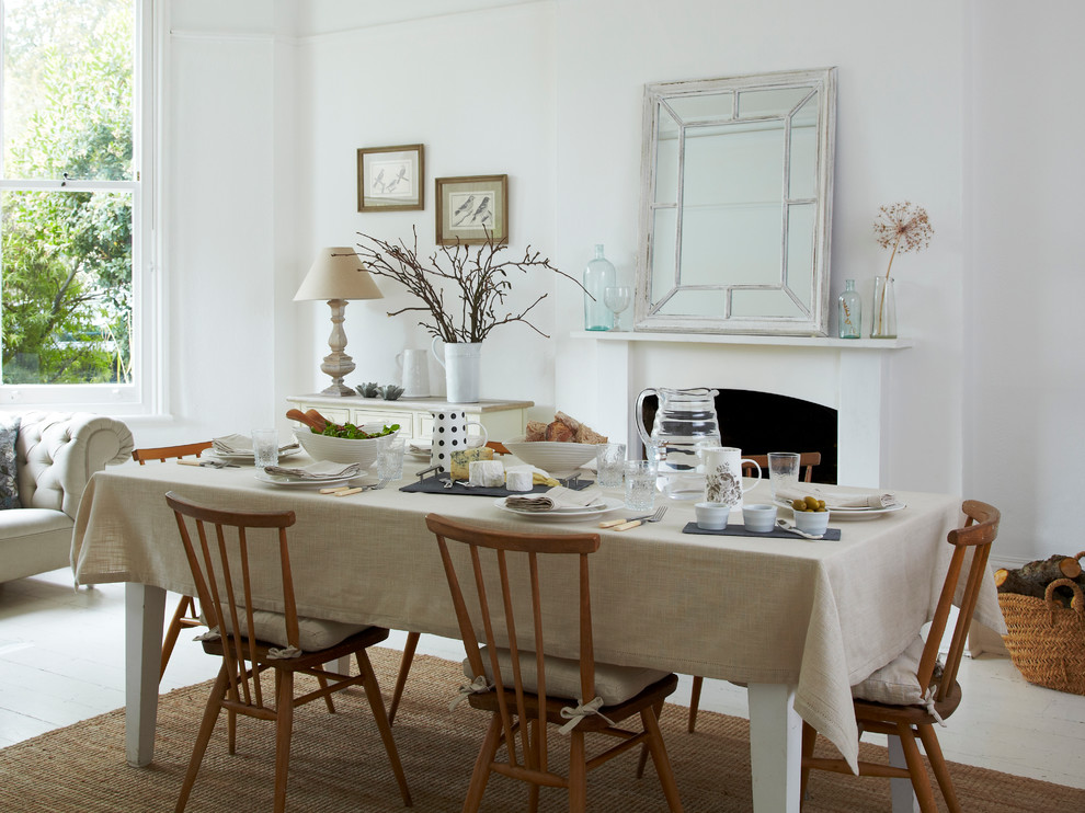 Example of a large danish light wood floor dining room design in London with white walls, a standard fireplace and a plaster fireplace