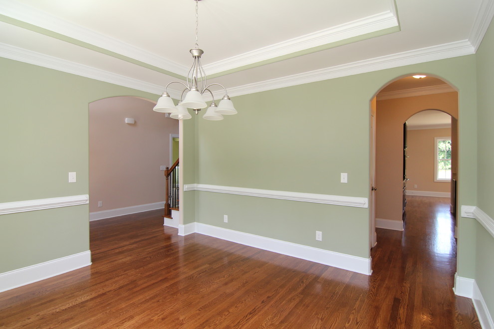 This is an example of a large traditional enclosed dining room in Raleigh with green walls and medium hardwood flooring.