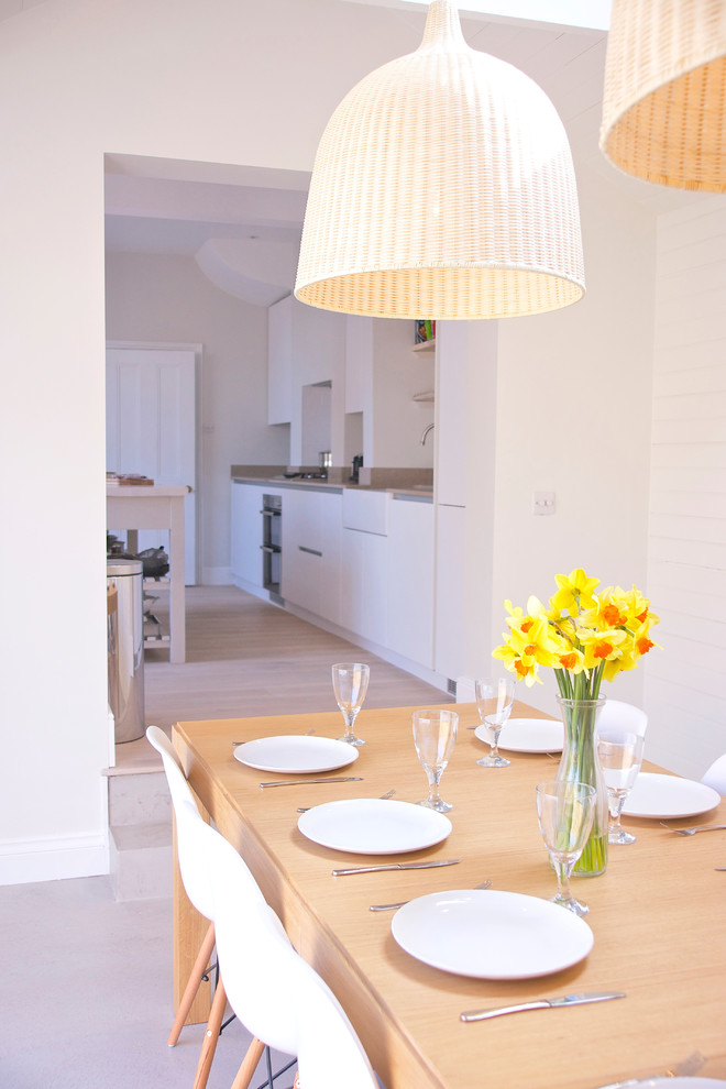 Immagine di una sala da pranzo aperta verso la cucina stile marino di medie dimensioni con pareti bianche, pavimento grigio, soffitto a volta e pannellatura