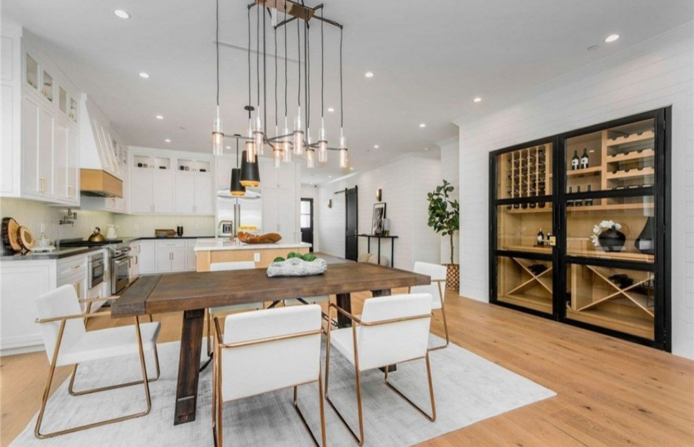 Esempio di una grande sala da pranzo aperta verso la cucina minimalista con pareti bianche, parquet chiaro e pavimento marrone