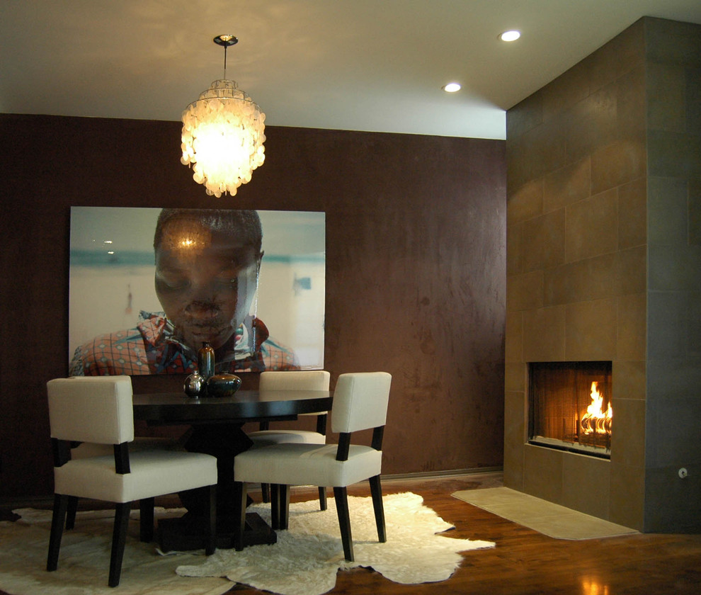 Exemple d'une salle à manger moderne avec parquet foncé, un manteau de cheminée en carrelage et une cheminée ribbon.