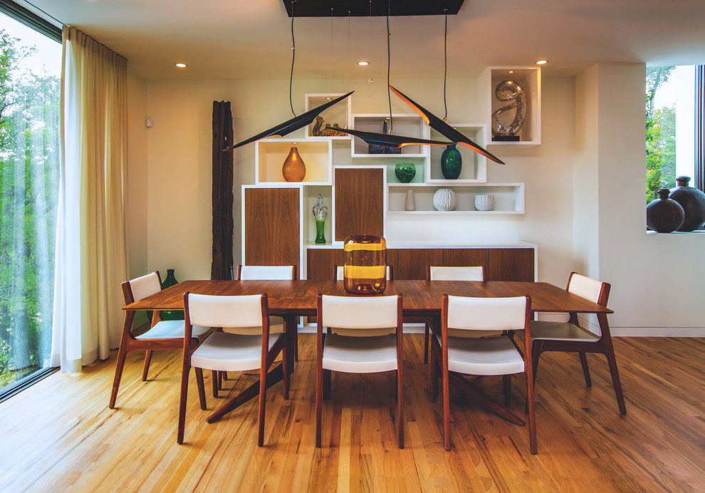 Cette photo montre une salle à manger ouverte sur le salon rétro de taille moyenne avec un mur blanc et un sol en bois brun.