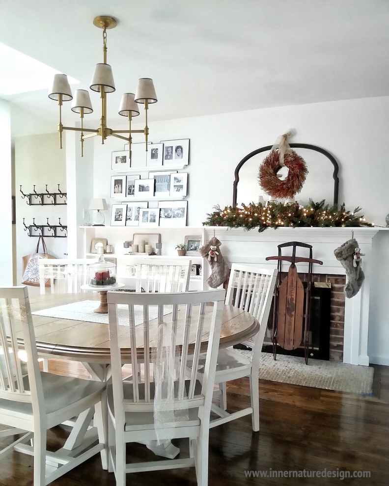 Immagine di una sala da pranzo aperta verso la cucina country di medie dimensioni con pareti bianche, parquet scuro, camino classico e cornice del camino in mattoni
