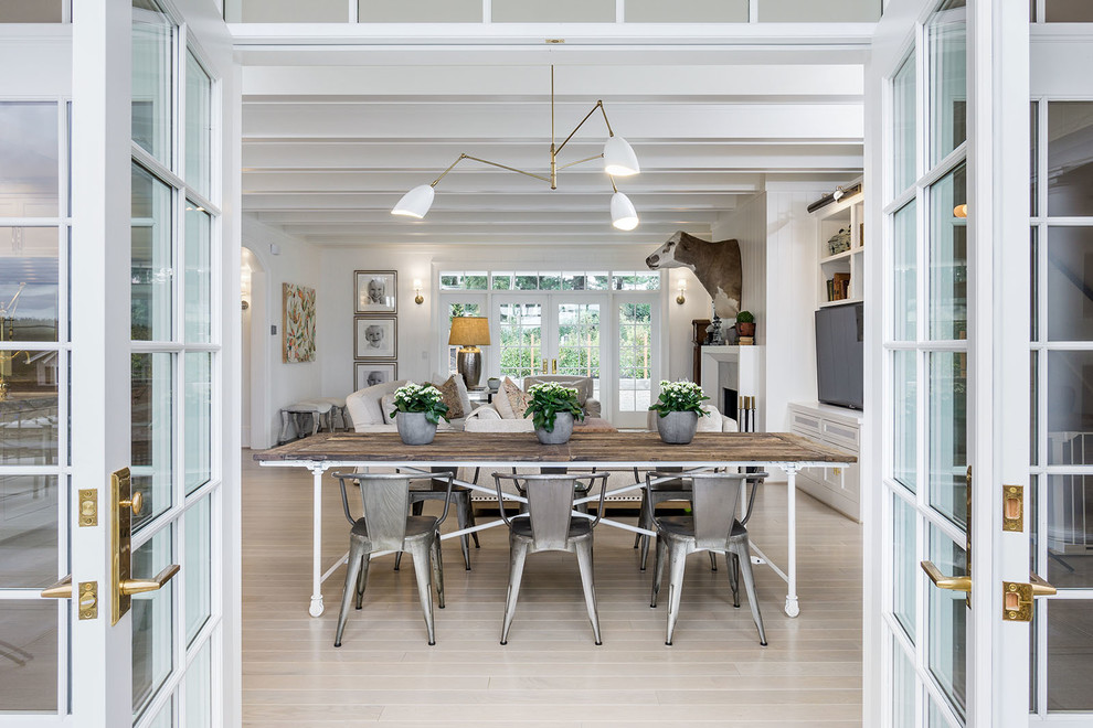 Foto di una sala da pranzo aperta verso il soggiorno country con pareti bianche, parquet chiaro e pavimento beige