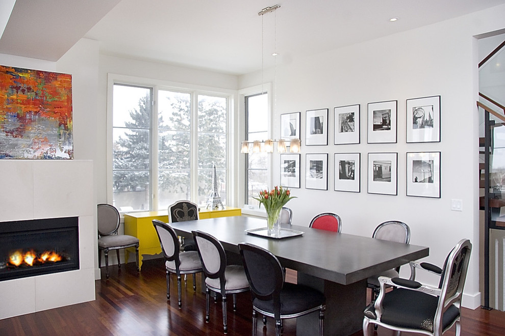 Example of a trendy dining room design in Calgary with a tile fireplace and white walls