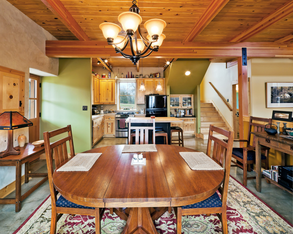 Ispirazione per una piccola sala da pranzo aperta verso la cucina rustica con pareti verdi e pavimento in cemento