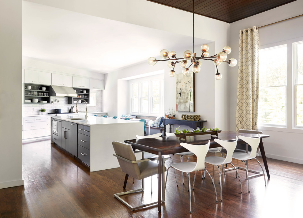 Immagine di una grande sala da pranzo aperta verso la cucina contemporanea con pareti bianche, pavimento in legno massello medio e pavimento marrone