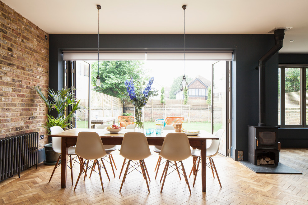 Aménagement d'une salle à manger ouverte sur le salon classique avec un mur bleu, parquet clair, un poêle à bois et un sol marron.