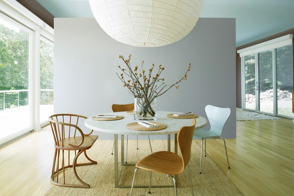 Cette photo montre une salle à manger tendance avec parquet clair, un sol marron et un mur gris.