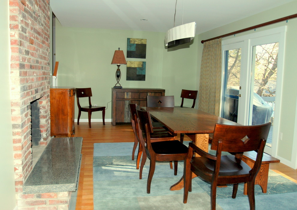 Foto di una sala da pranzo aperta verso il soggiorno chic di medie dimensioni con pareti verdi, parquet chiaro, camino classico e cornice del camino in mattoni