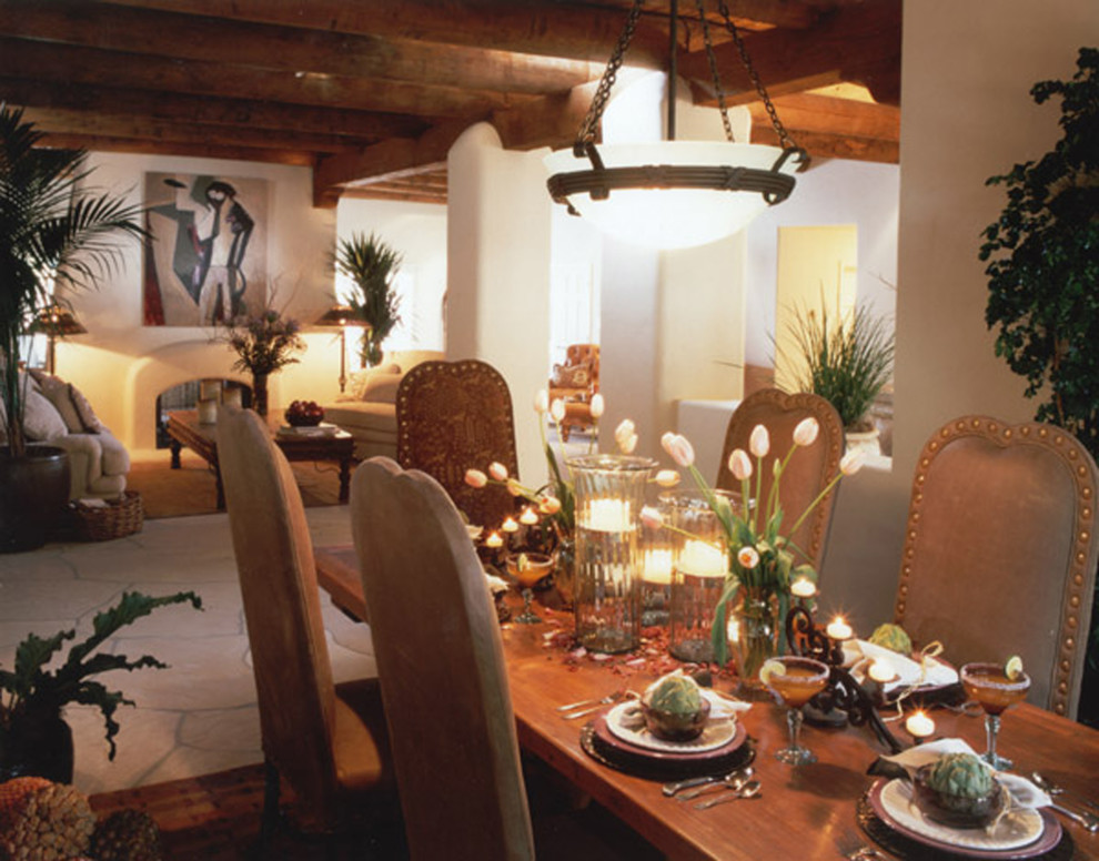 Idée de décoration pour une grande salle à manger ouverte sur le salon sud-ouest américain avec un mur jaune, une cheminée double-face et un manteau de cheminée en plâtre.