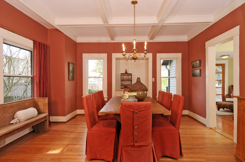 Imagen de comedor tradicional con paredes rojas y suelo de madera en tonos medios