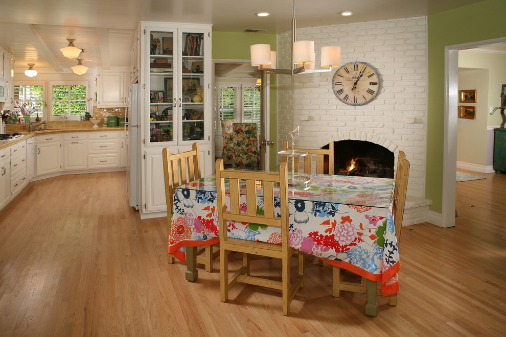 Exemple d'une salle à manger ouverte sur le salon tendance avec un manteau de cheminée en brique, une cheminée d'angle et éclairage.