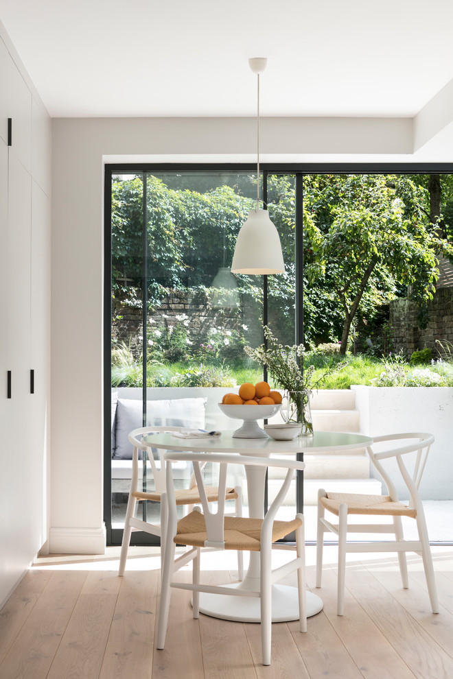 Foto di una piccola sala da pranzo aperta verso la cucina scandinava con parquet chiaro, pareti bianche e pavimento beige