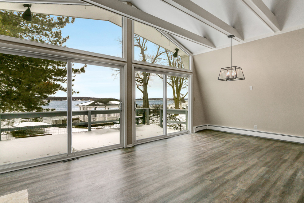 Cette photo montre une salle à manger ouverte sur le salon bord de mer de taille moyenne avec un sol en vinyl, un mur beige, une cheminée standard, un manteau de cheminée en carrelage et un sol marron.