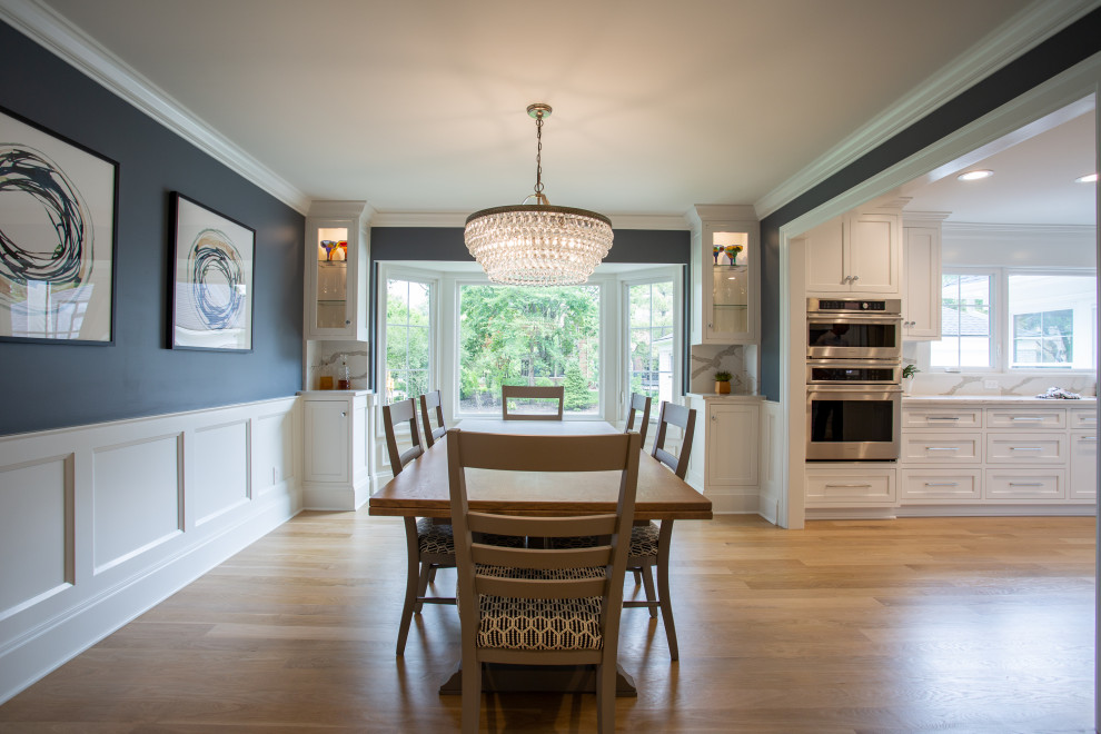 Ispirazione per una sala da pranzo aperta verso la cucina chic di medie dimensioni con pareti blu, parquet chiaro, pavimento beige e pannellatura