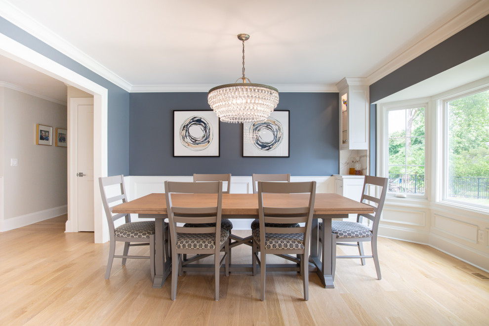 Foto di una sala da pranzo aperta verso la cucina tradizionale di medie dimensioni con pareti blu, parquet chiaro, pavimento beige e pannellatura