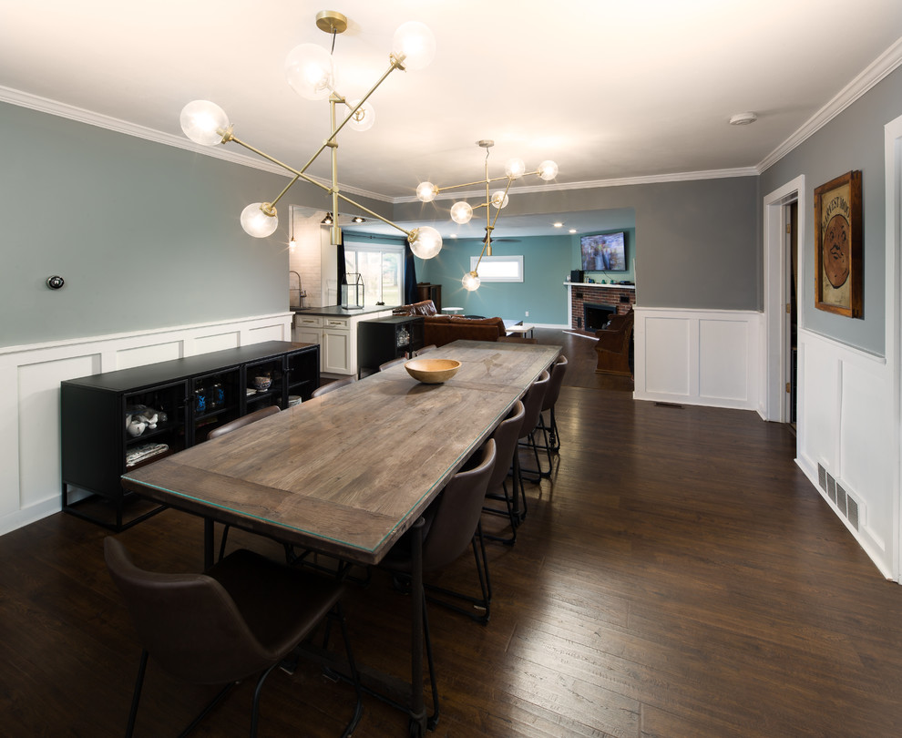 Réalisation d'une grande salle à manger ouverte sur la cuisine design avec un mur gris, sol en stratifié, une cheminée standard, un manteau de cheminée en bois et un sol marron.
