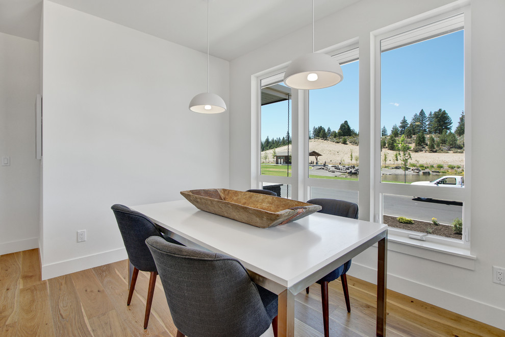 Foto di una sala da pranzo aperta verso la cucina minimal di medie dimensioni con pareti bianche e parquet chiaro