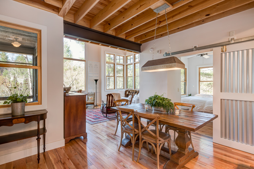 Esempio di una sala da pranzo aperta verso il soggiorno stile rurale con pareti bianche, pavimento in legno massello medio e pavimento marrone