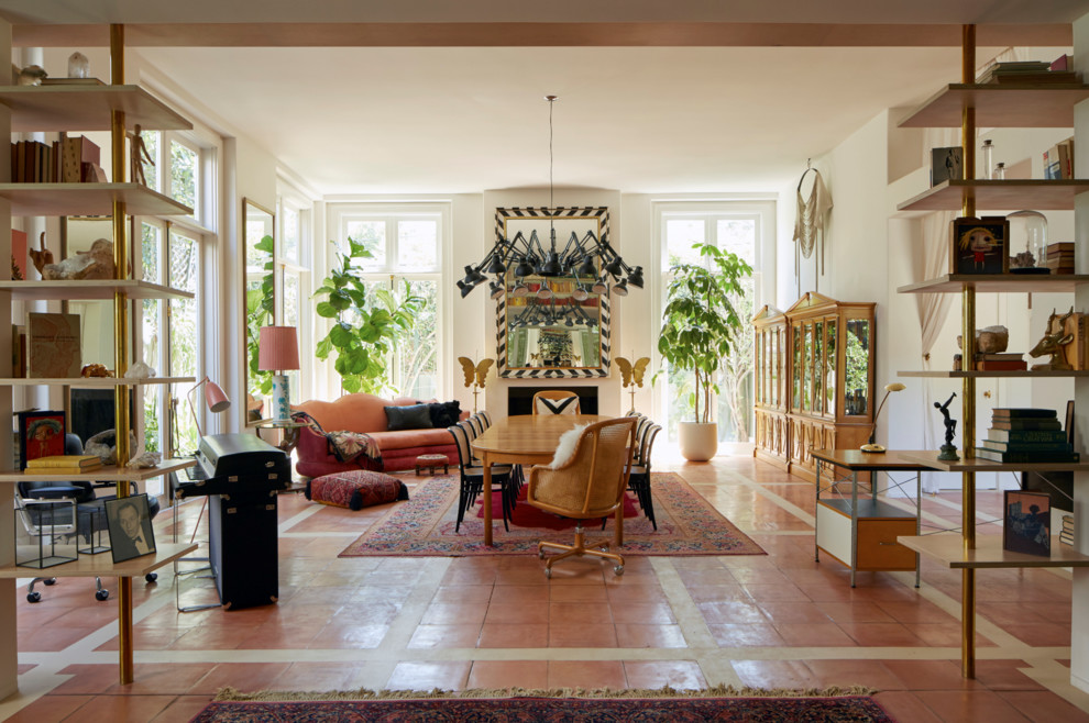 Пример оригинального дизайна: большая гостиная-столовая в стиле фьюжн с белыми стенами, полом из терракотовой плитки, стандартным камином, фасадом камина из штукатурки и оранжевым полом