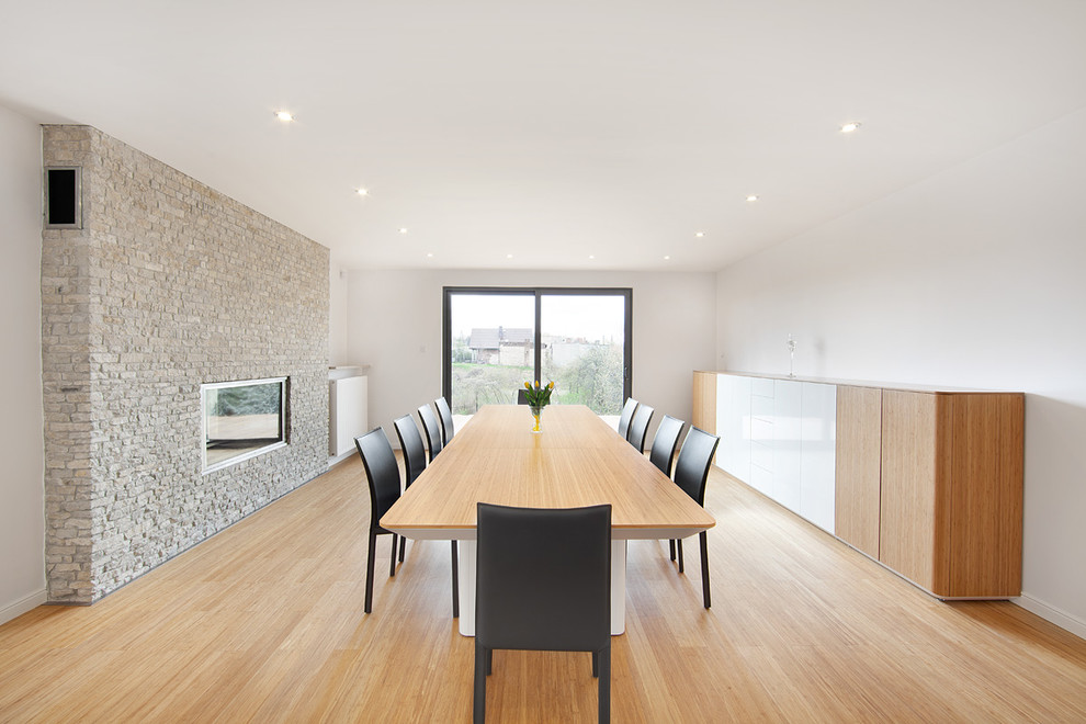 Idee per una sala da pranzo minimalista con pareti bianche, parquet chiaro e camino classico