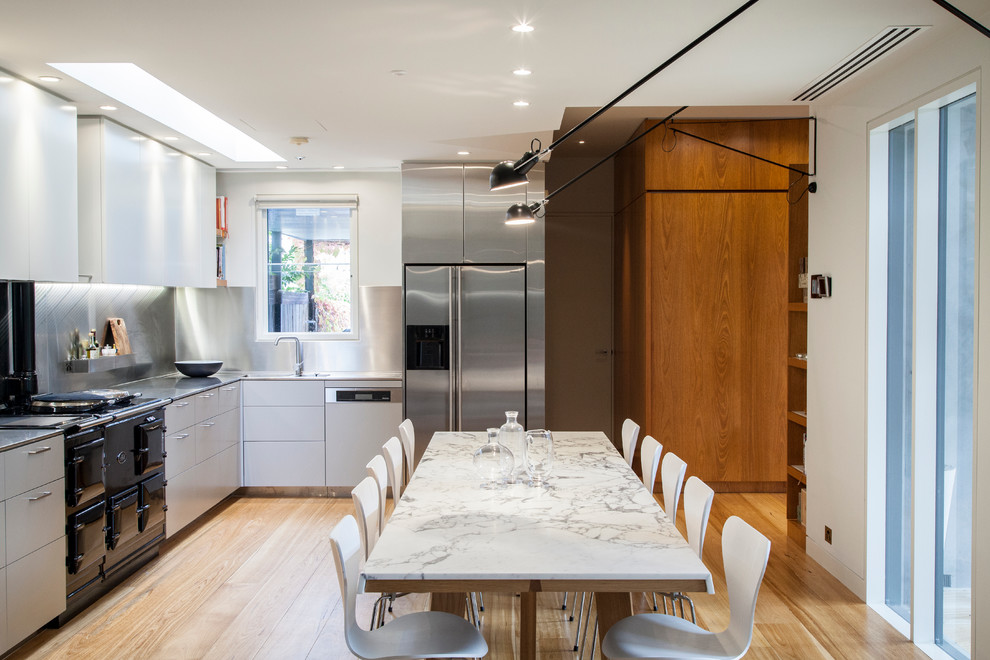 Cette image montre une salle à manger ouverte sur la cuisine design avec un mur blanc et un sol en bois brun.