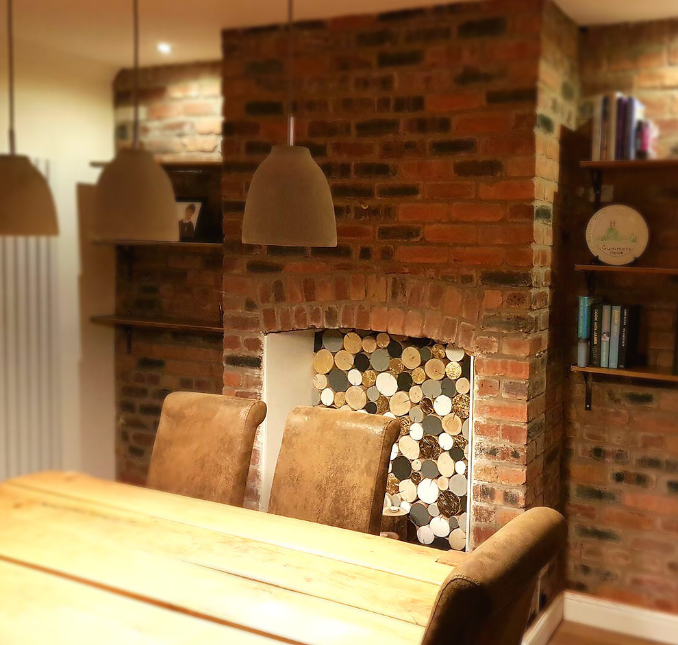 Mid-sized trendy light wood floor enclosed dining room photo in Gloucestershire with white walls, a two-sided fireplace and a brick fireplace