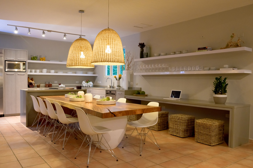 Cette image montre une salle à manger ouverte sur la cuisine marine avec un mur gris et tomettes au sol.