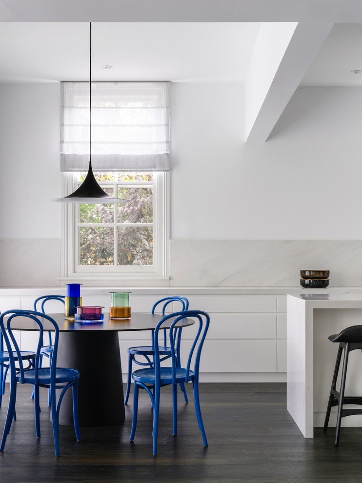 Immagine di una sala da pranzo aperta verso la cucina minimal con pareti bianche, parquet scuro e pavimento nero