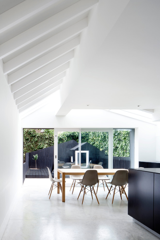 Пример оригинального дизайна: кухня-столовая в современном стиле с белыми стенами и бетонным полом без камина
