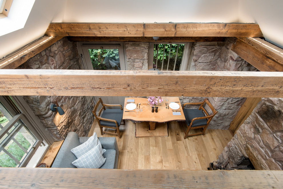 Inspiration pour une petite salle à manger bohème fermée avec un sol en bois brun et un manteau de cheminée en pierre.