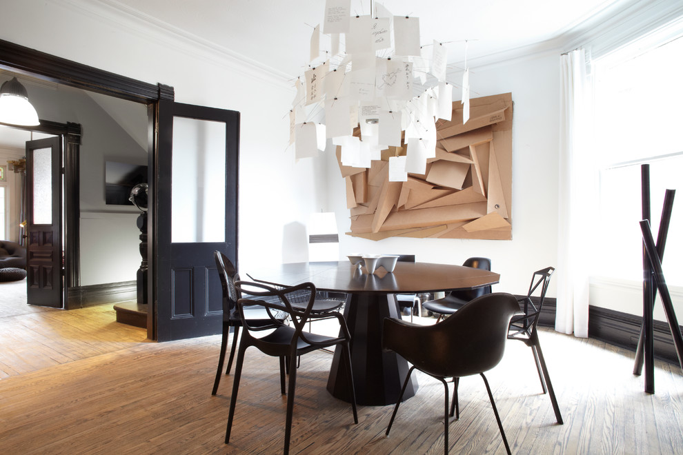 Immagine di una sala da pranzo minimal chiusa con pareti bianche, pavimento in legno massello medio e nessun camino
