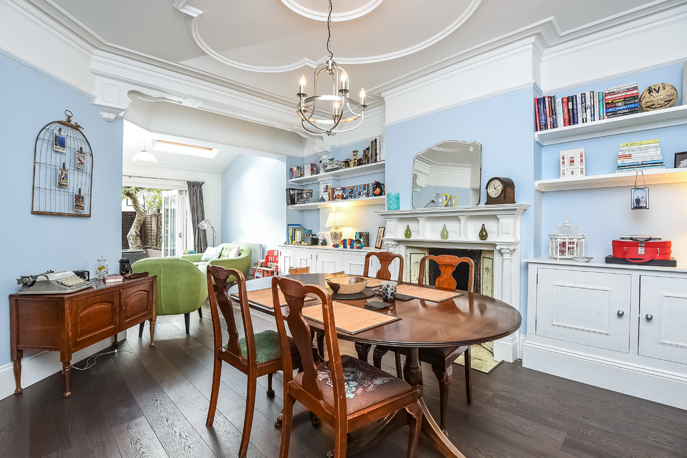 Exemple d'une salle à manger chic de taille moyenne avec parquet foncé, une cheminée standard, un sol marron et un mur bleu.