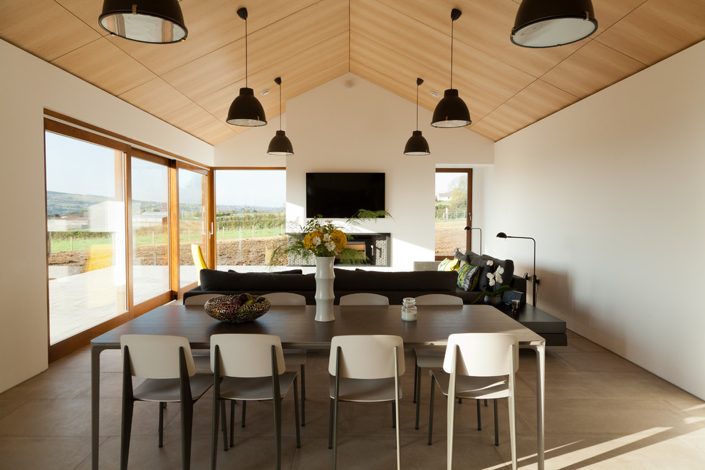 Inspiration pour une salle à manger ouverte sur le salon design de taille moyenne avec un mur blanc, une cheminée d'angle et un sol gris.