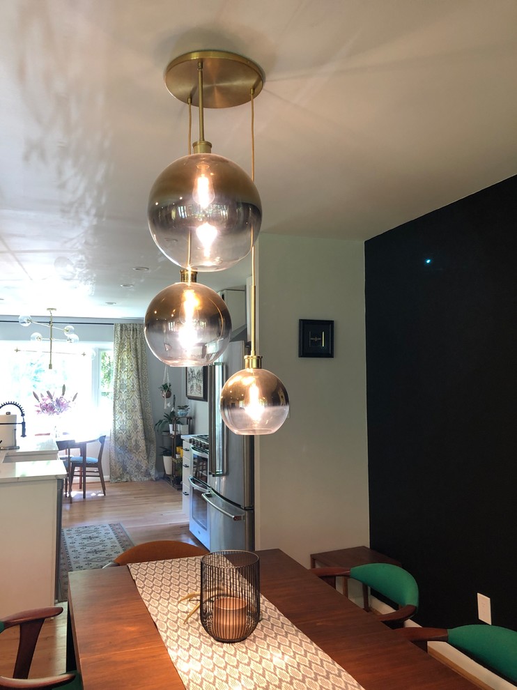 Foto di una sala da pranzo aperta verso la cucina moderna di medie dimensioni con pareti nere, parquet chiaro e pavimento beige