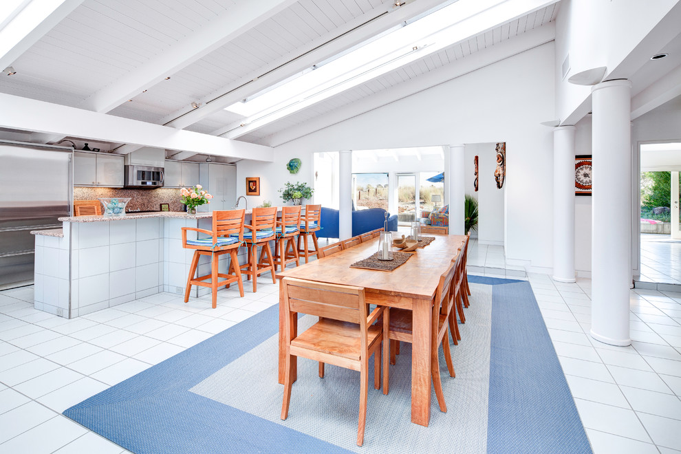 Immagine di una grande sala da pranzo aperta verso il soggiorno stile marino con pareti bianche e pavimento in gres porcellanato