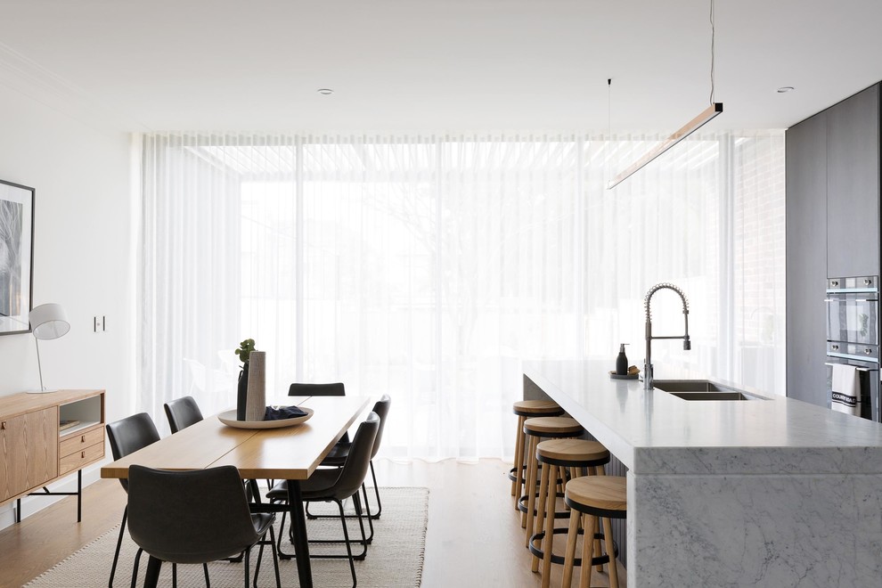 Exemple d'une salle à manger ouverte sur la cuisine tendance avec un mur blanc.