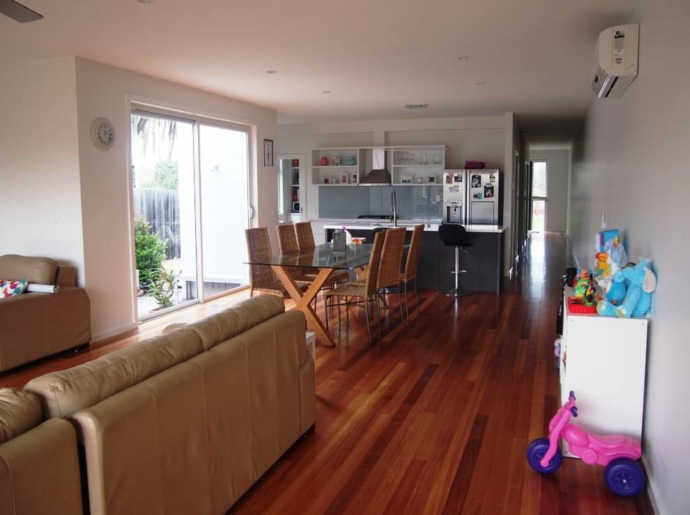 Immagine di una sala da pranzo aperta verso la cucina minimalista con pareti bianche e pavimento in legno massello medio