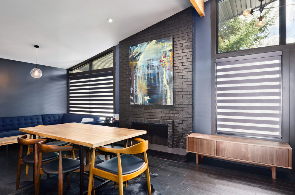 Inspiration pour une grande salle à manger ouverte sur le salon urbaine avec un mur bleu, parquet foncé, une cheminée standard, un manteau de cheminée en brique et un sol marron.