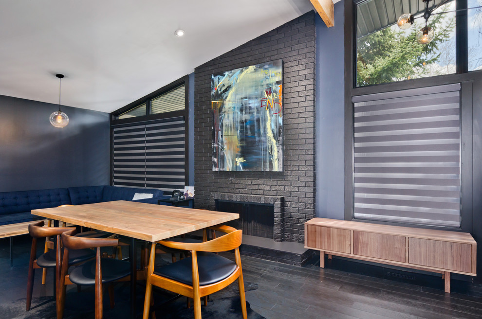 Idée de décoration pour une grande salle à manger ouverte sur le salon design avec un mur bleu, parquet foncé, une cheminée standard, un manteau de cheminée en brique et un sol marron.